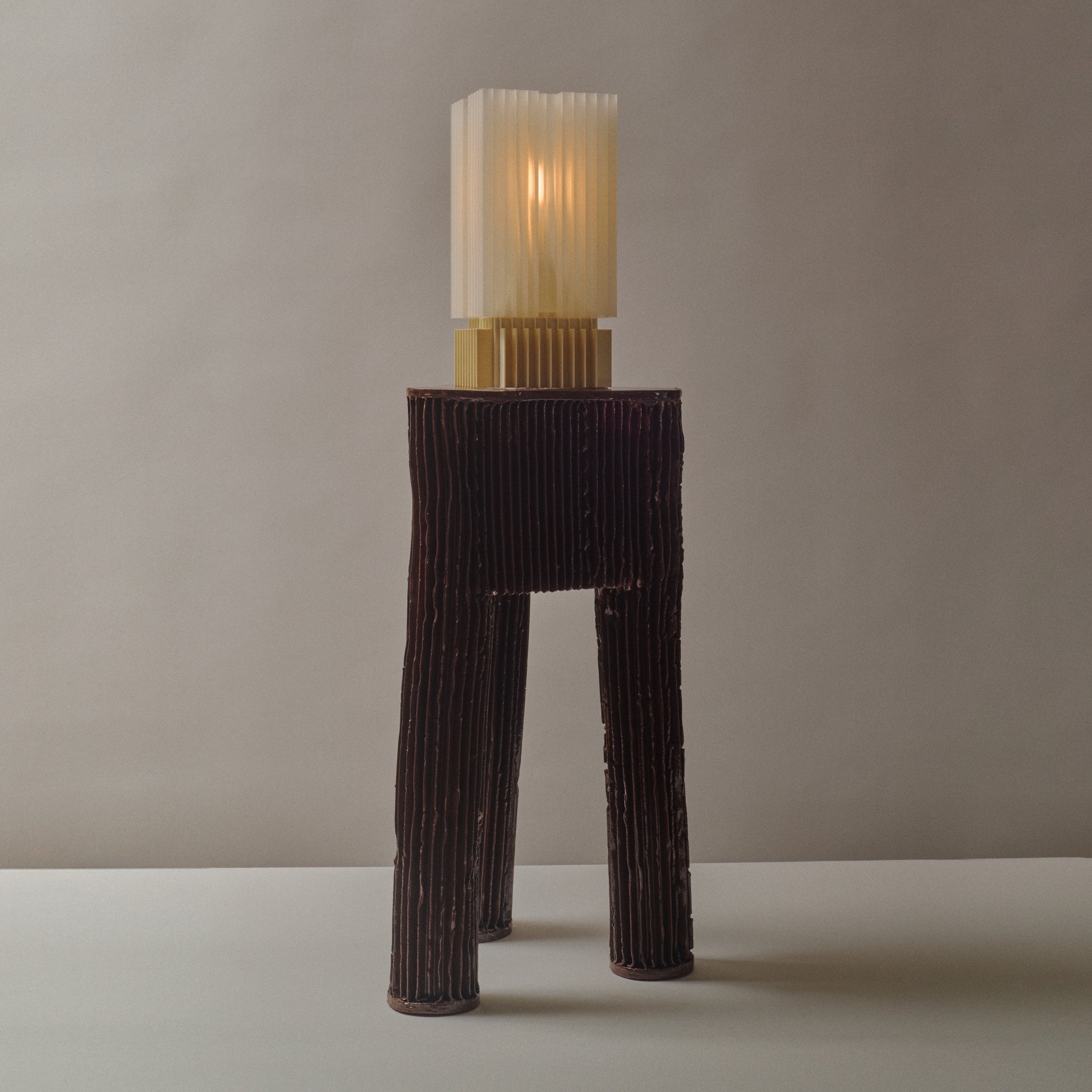 Tall, ribbed lamp with a textured base and cylindrical shade on a neutral background