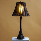 Black table lamp with pleated shade on a beige background