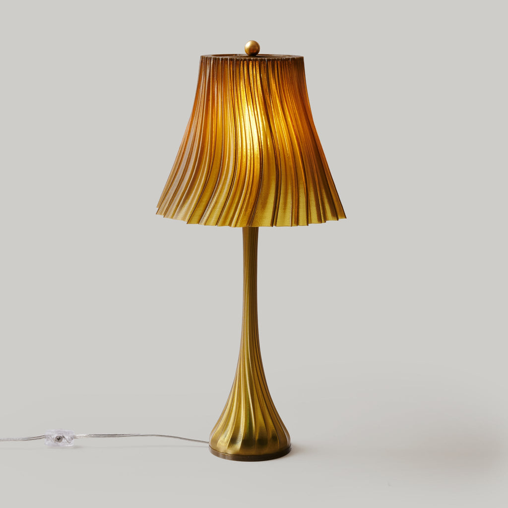 Gold table lamp with ribbed shade on a light gray background