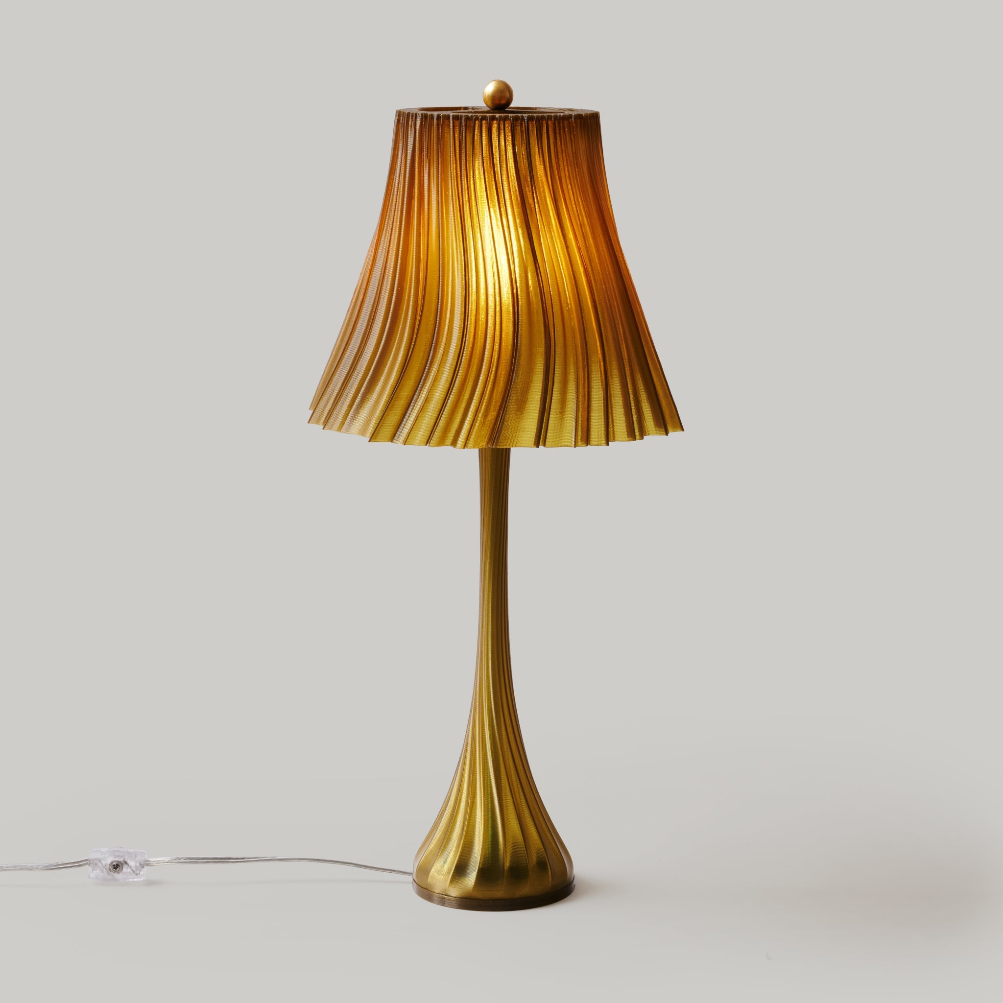 Gold table lamp with ribbed shade on a light gray background