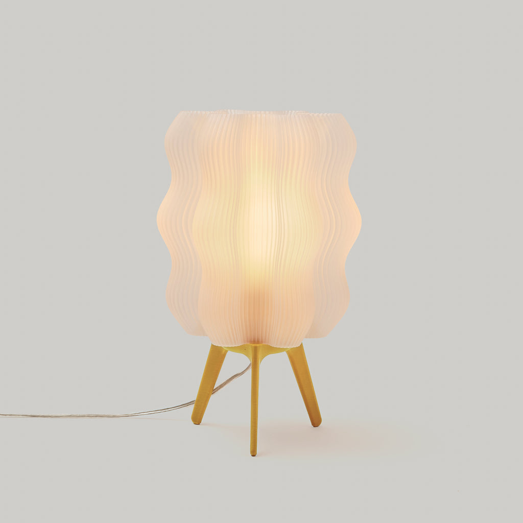 Table lamp with a textured white shade and yellow base on a light gray background