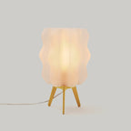 Table lamp with a textured white shade and yellow base on a light gray background