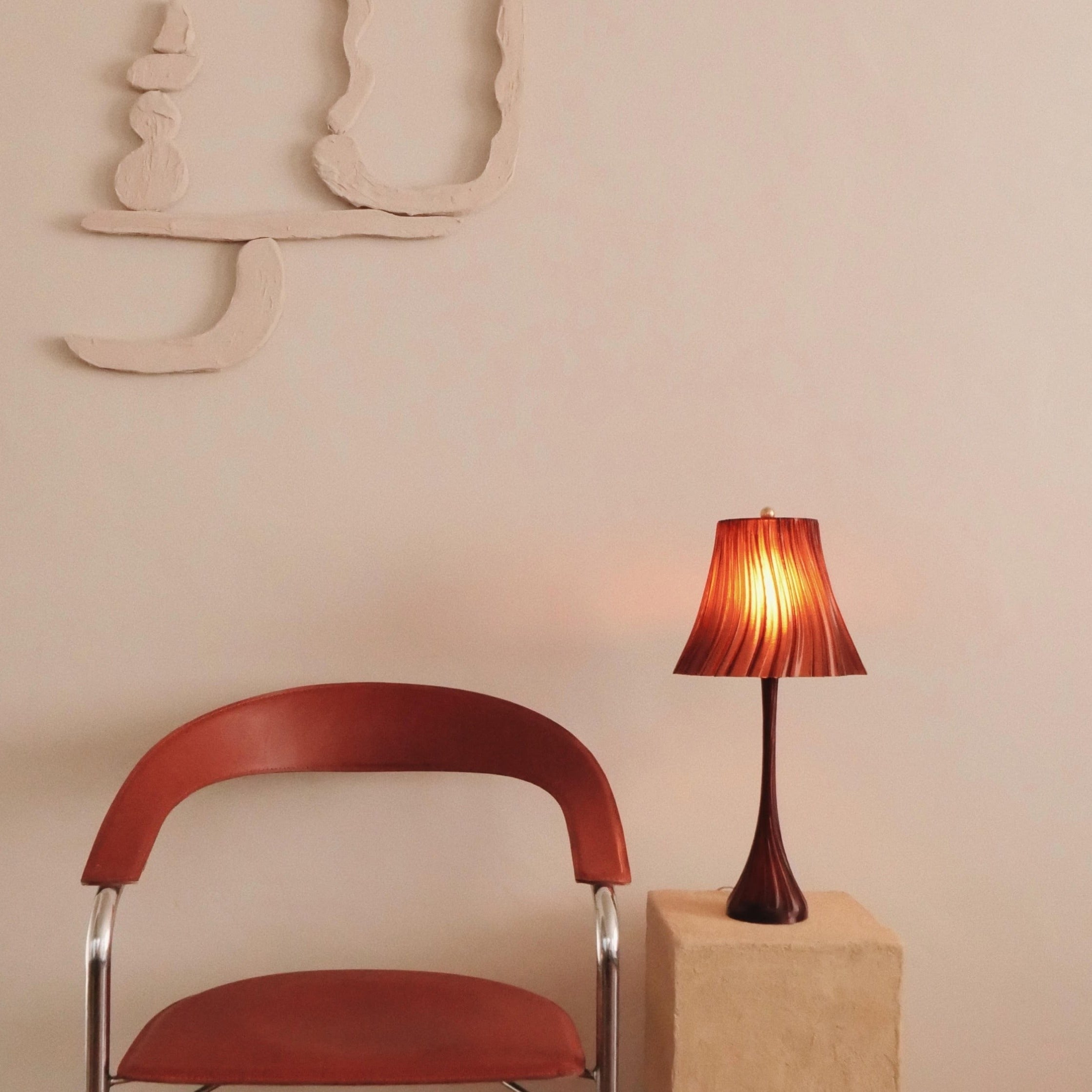 Red chair and lamp against a beige wall