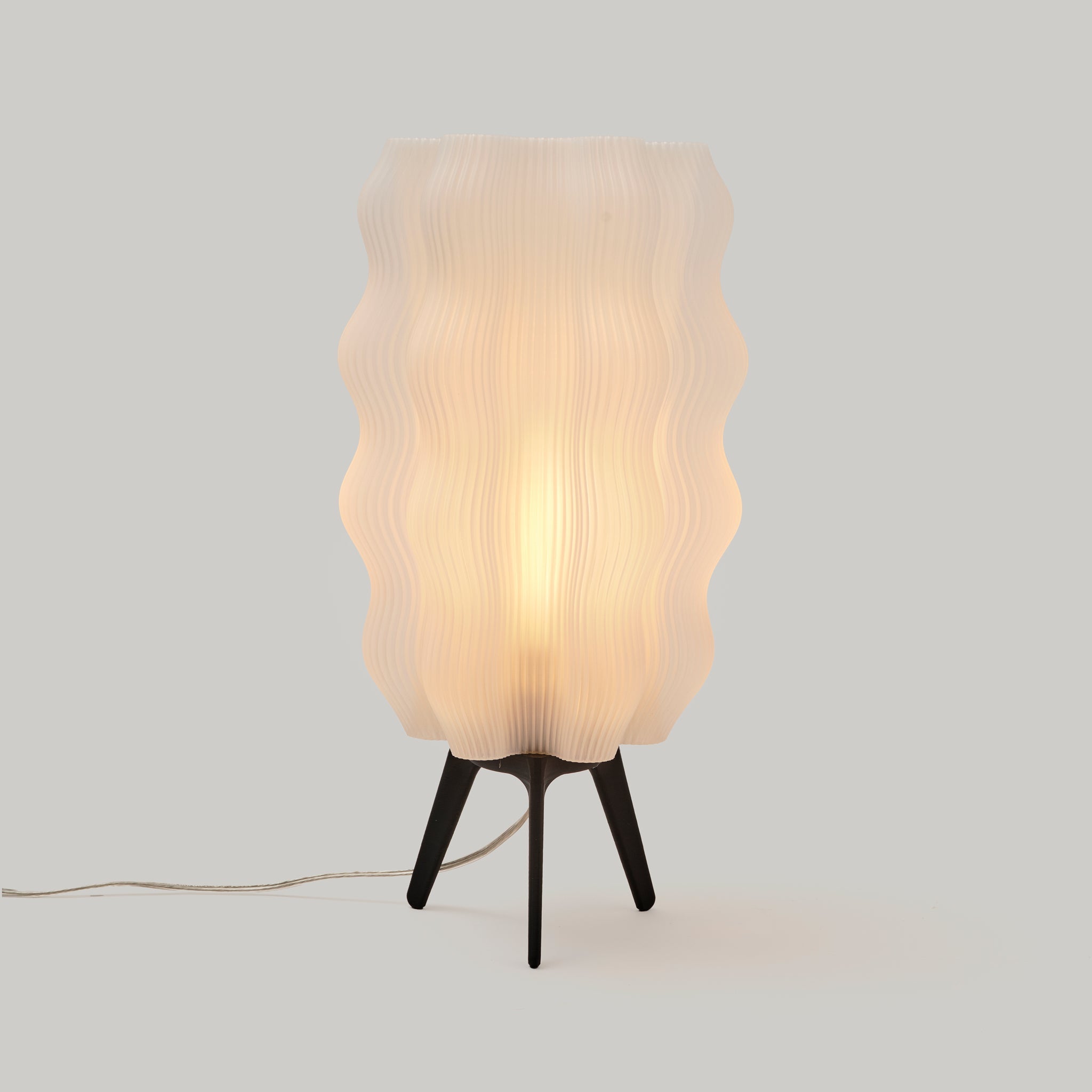 Table lamp with wavy plastic shade on a plain background