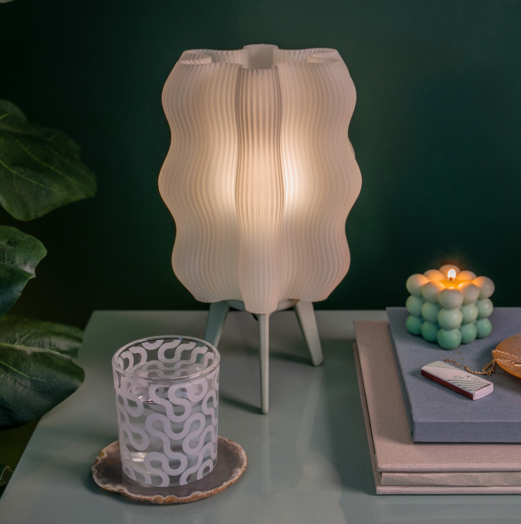 Wavy-patterned lamp on a table with decorative items against a dark background