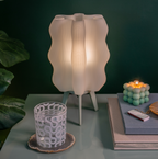 Wavy-patterned lamp on a table with decorative items against a dark background